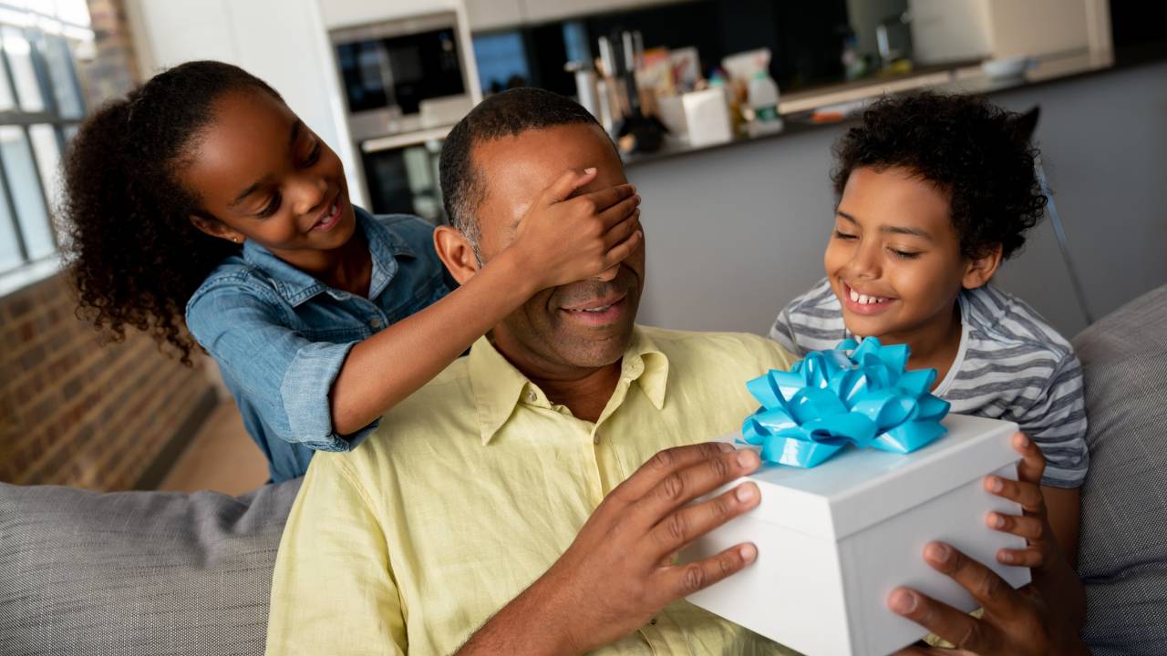 Um casal de crianças dando um presente surpresa para o pai