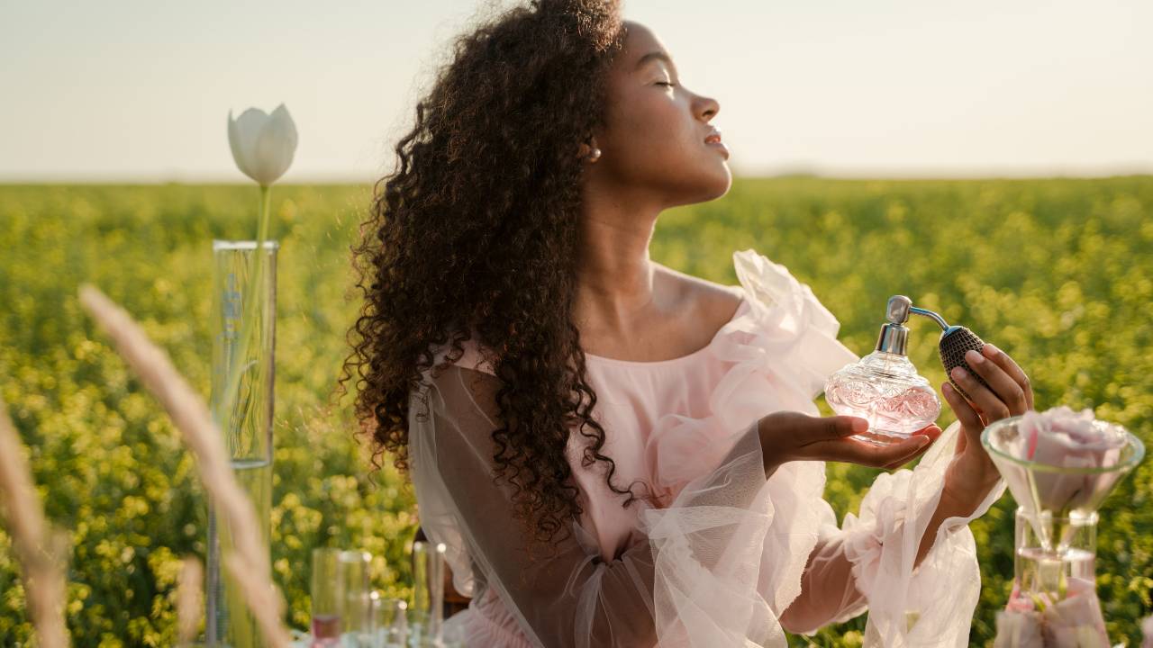 Mulher negra se perfumando em um campo aberto em um dia quente