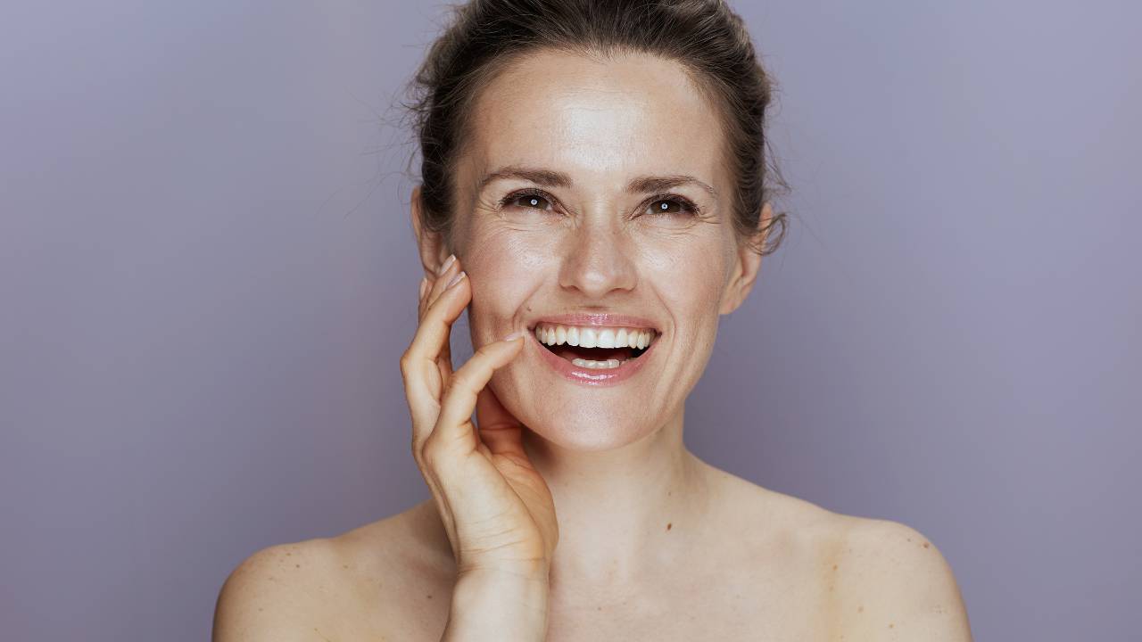 Close no rosto de uma mulher sorridente de cerca de 40 anos